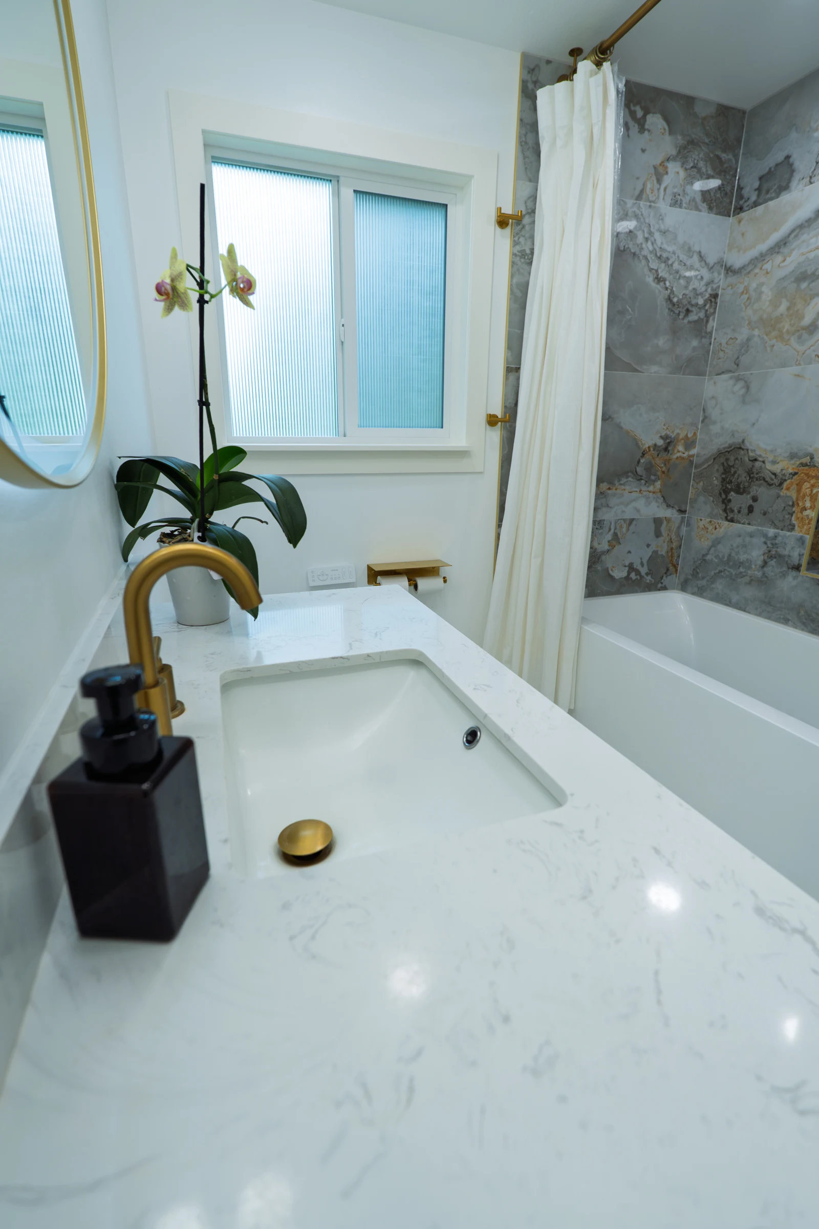 Bathroom vanity, window, bathtub, and marble surround with brass fixtures, Portland OR